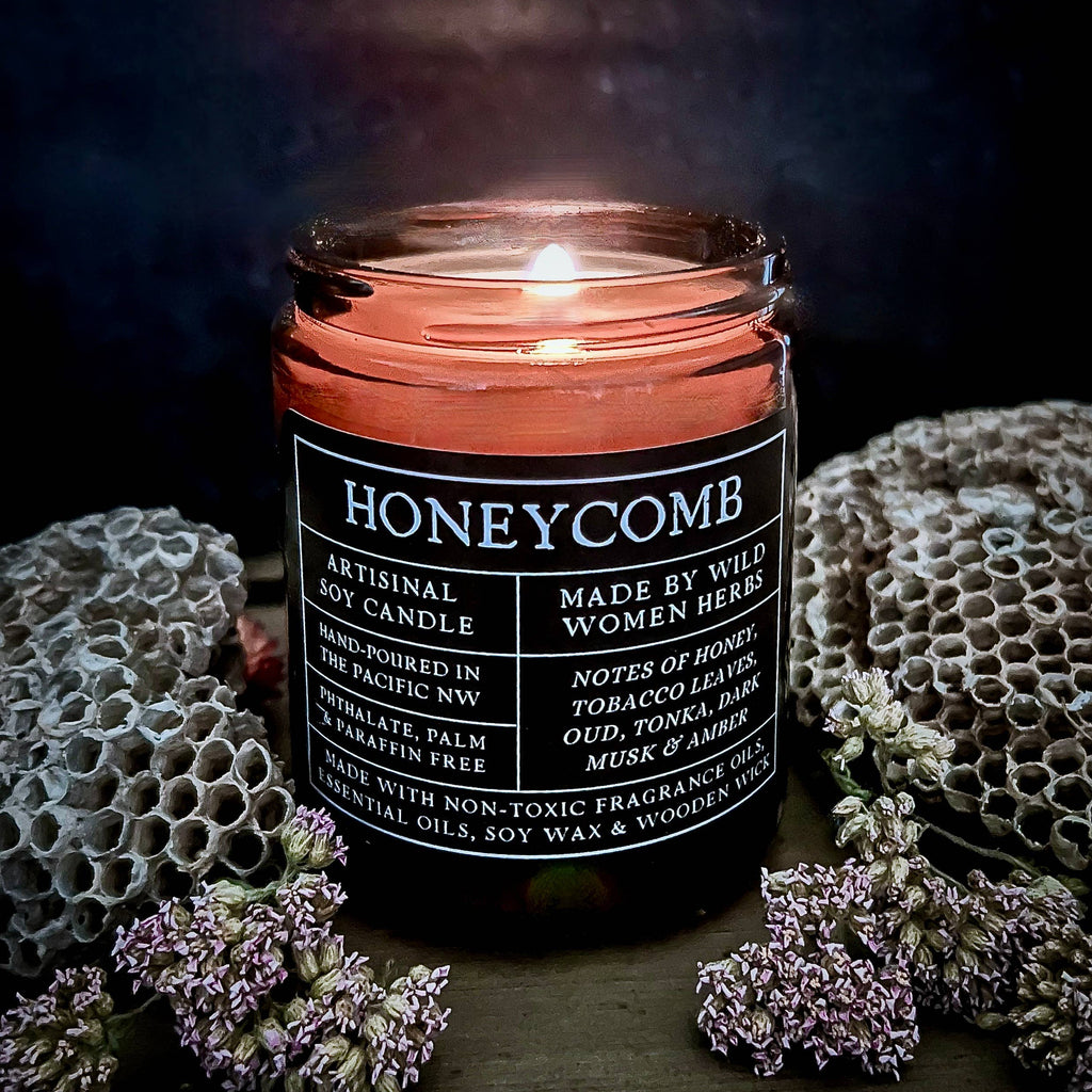 Honeycomb candle with a label surrounded by honeycomb and flowers on a dark background