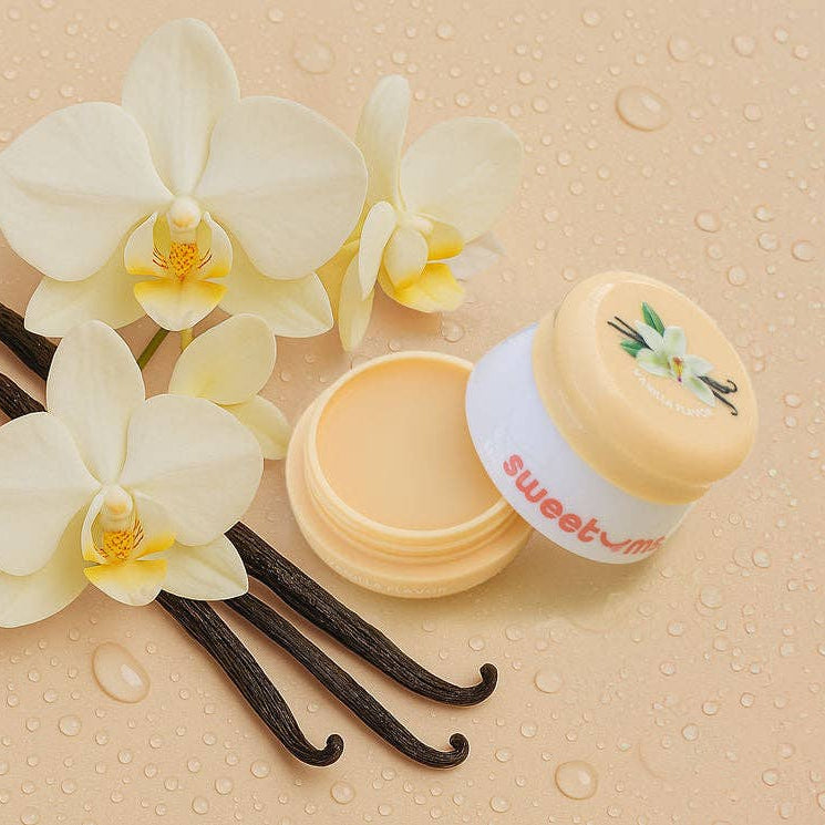 Vanilla-flavored product with vanilla beans and orchids on a beige background