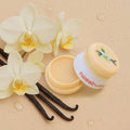Vanilla-flavored product with vanilla beans and orchids on a beige background