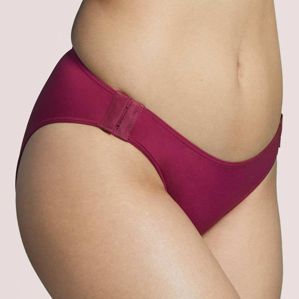 Side view of a model wearing plum color panties with a wide thong back.