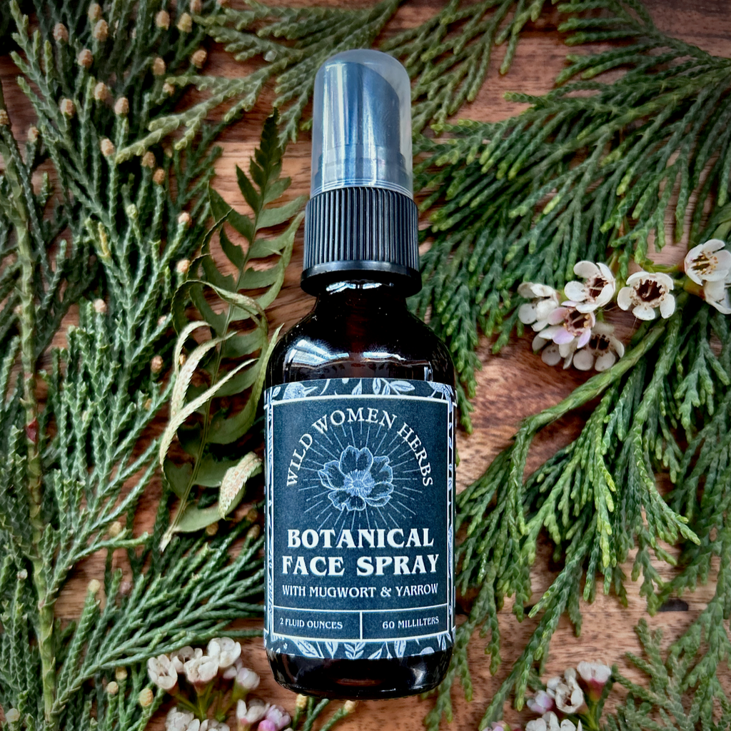 Botanical face spray bottle on a wooden surface with greenery and flowers