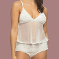 A woman modeling a white sheer lingerie set with ruffled trim, featuring a camisole-style top and matching high-waisted briefs, against a plain white background.
