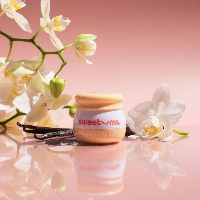 Jar of lip balm with a white label on a pink background with flowers