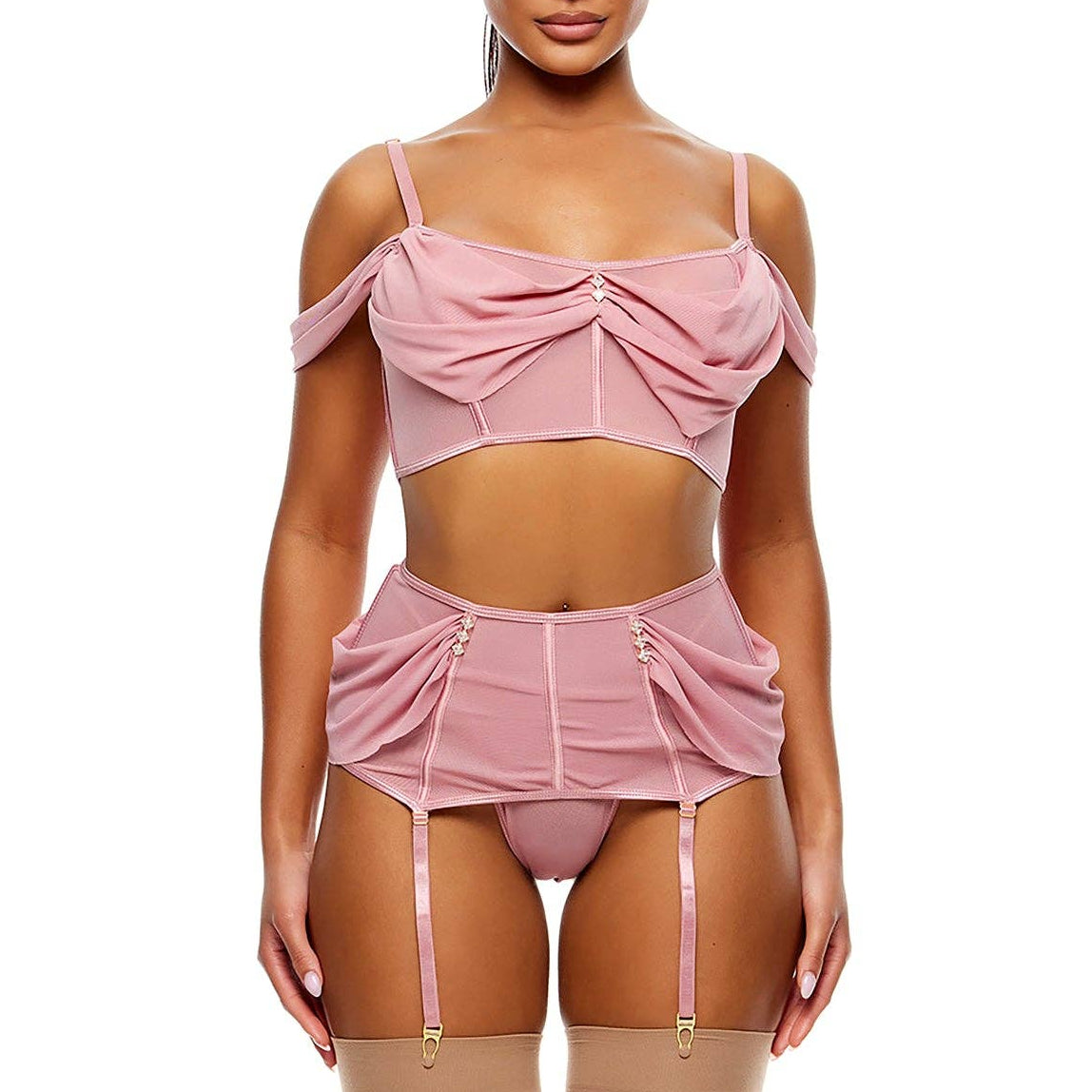 A model wearing a pink lingerie set consisting of a cold-shoulder crop top with a front bow, a matching high-waisted garter belt with front buttons, a matching panty, and sheer thigh-high stockings, paired with clear platform heels against a white background.