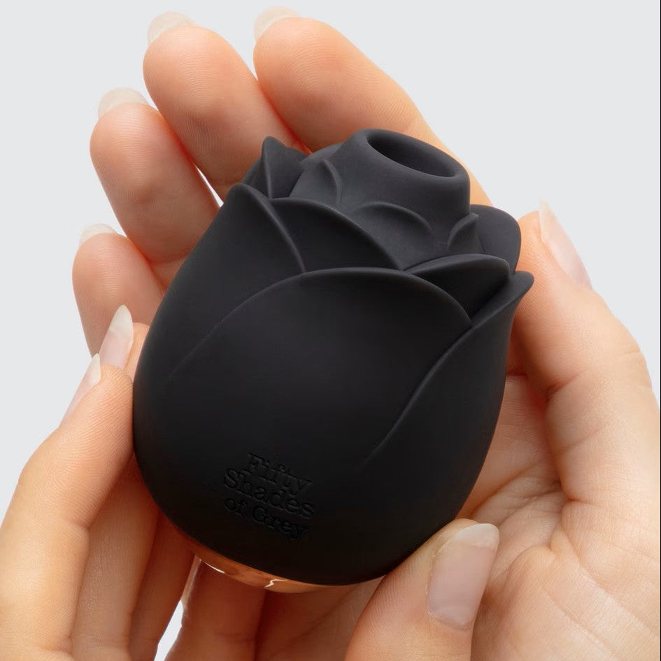 Black rose-shaped object held in hands against a light gray background