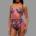 Woman wearing a floral bra, garter and thong set with pink accents on a white background