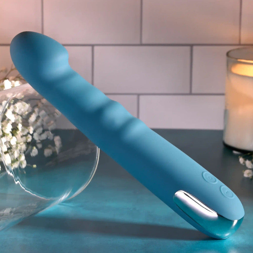 Blue handheld electronic device on a table with a candle and flowers in the background