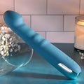 Blue handheld electronic device on a table with a candle and flowers in the background