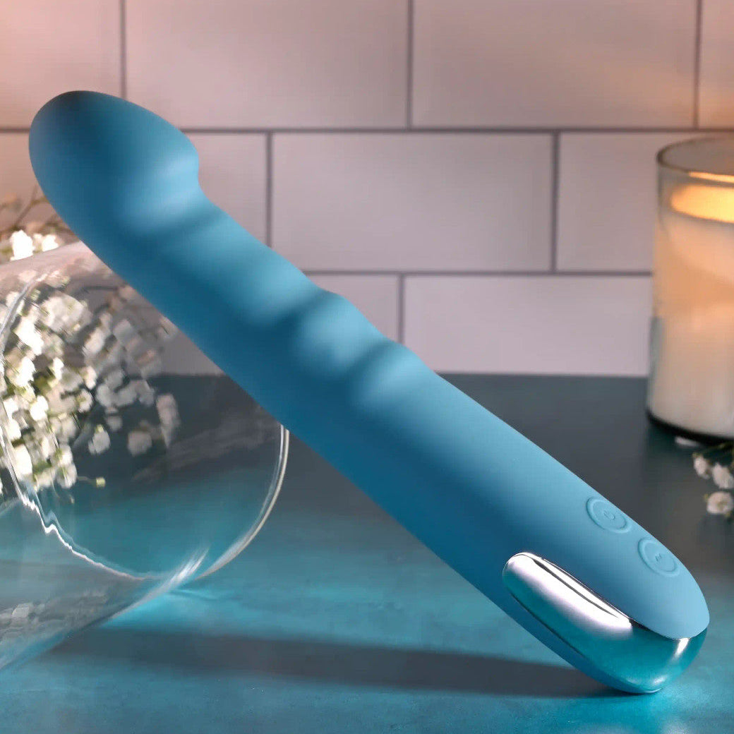 Blue handheld electronic device on a table with a candle and flowers in the background