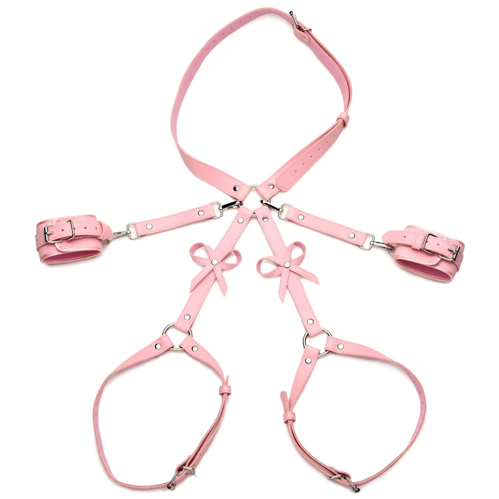 Pink faux leather harness set with matching wrist cuffs and thigh straps, featuring silver metal buckles and decorative bows, displayed on a solid white background.