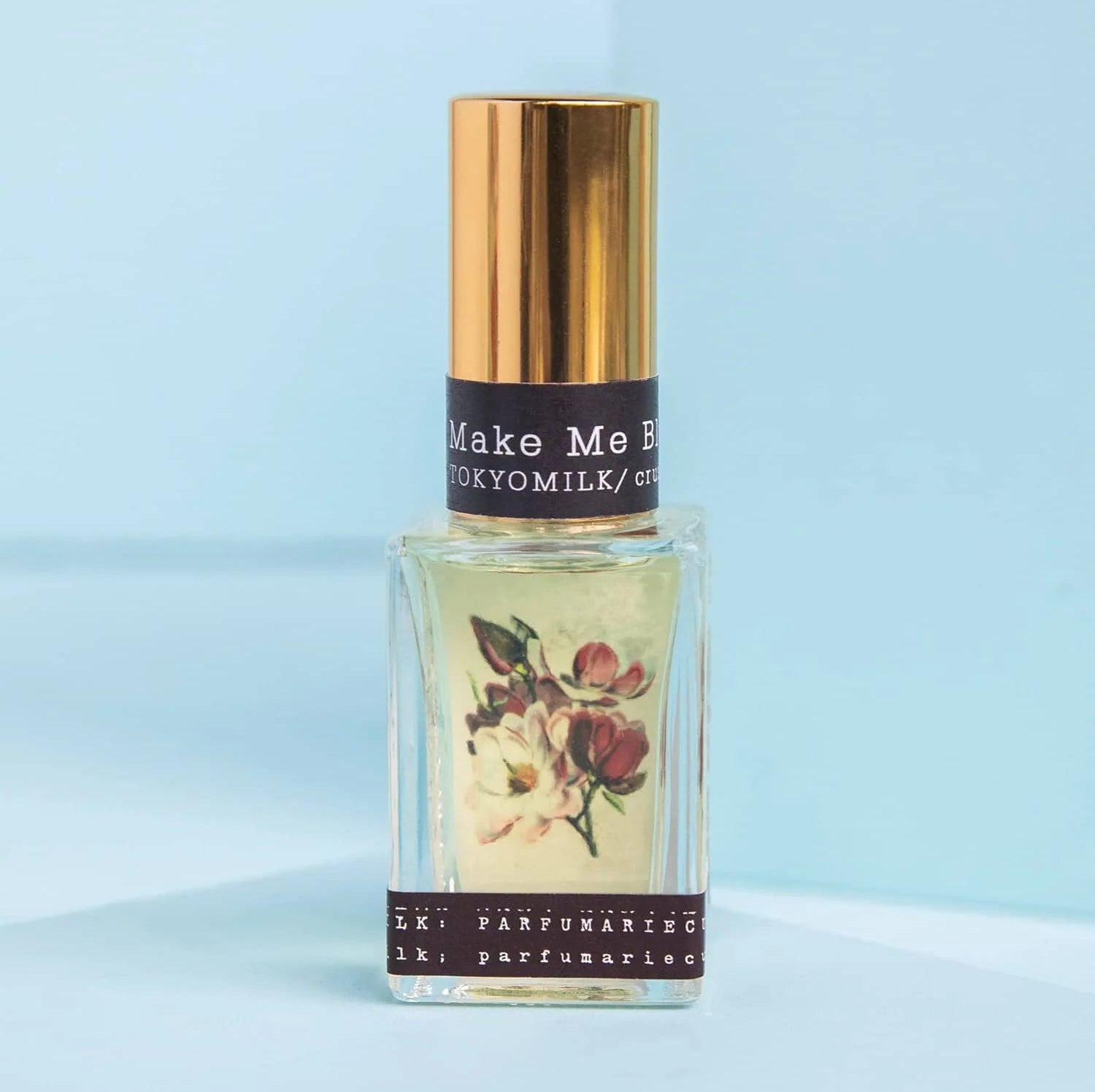 Perfume bottle with floral label on a light blue background