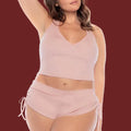 Woman wearing a pink sleepwear set featuring a short tank top and short.