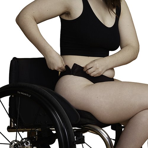 Model in a wheelchair, fastening the hip closure on her panties.