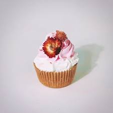 A bath bomb shaped exactly like a sweet cupcake, but with floral herds as decoration.