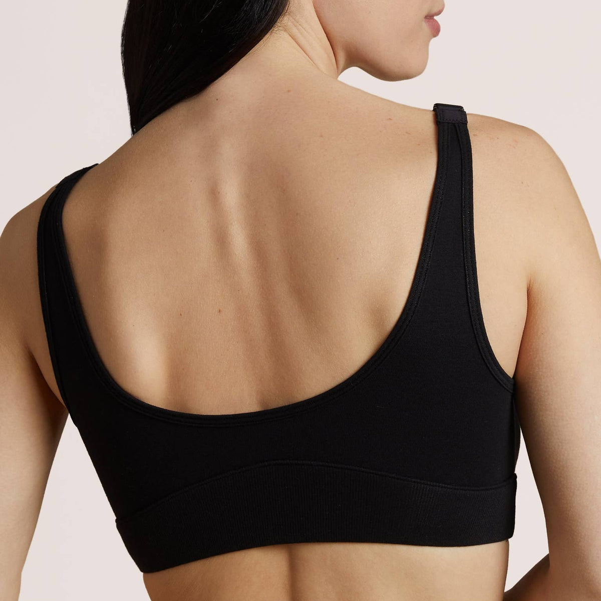 A woman with long dark hair is shown from the back wearing a black bra.
