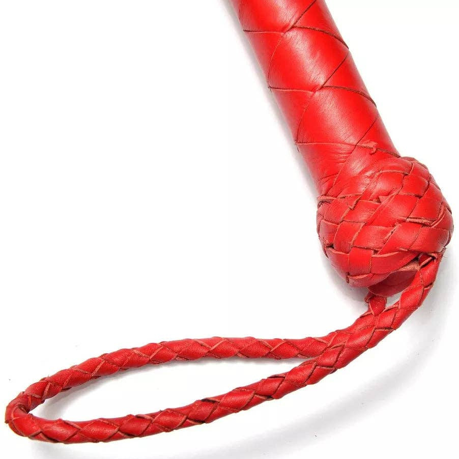 A close-up of a bright red leather flogger or whip with a braided loop handle, shown on a plain white background.