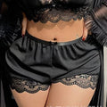 Person wearing black lace lingerie set with sheer robe in a bedroom setting