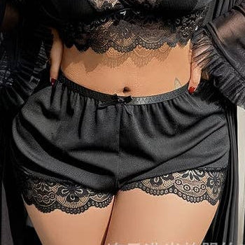Person wearing black lace lingerie set with sheer robe in a bedroom setting