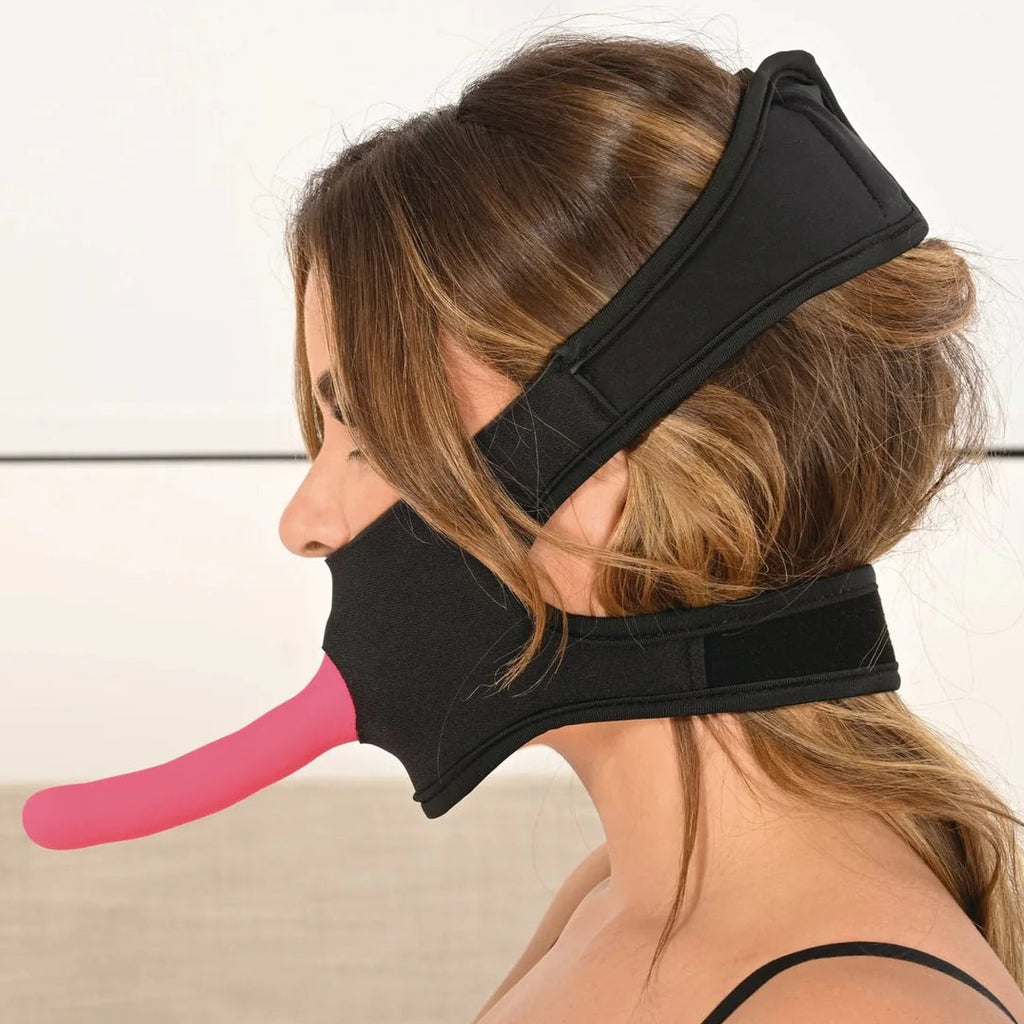 Side view of the gag, with a dildo facing out of the mouth hole and two secure straps holing it in pace behind the neck and at the top of her head.