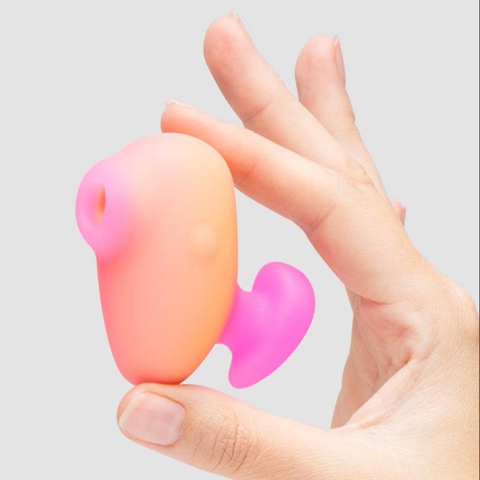 Hand holding a pink and orange object against a light gray background