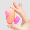 Hand holding a pink and orange object against a light gray background