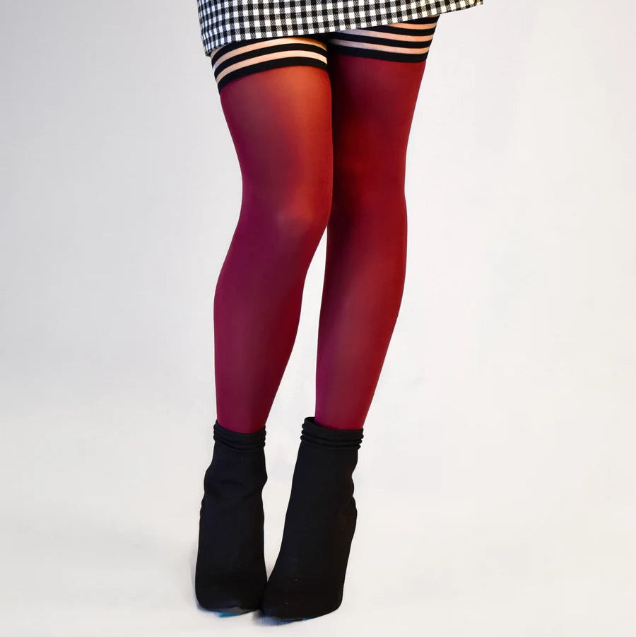 Person wearing a checkered skirt, red tights, and black shoes on a white background
