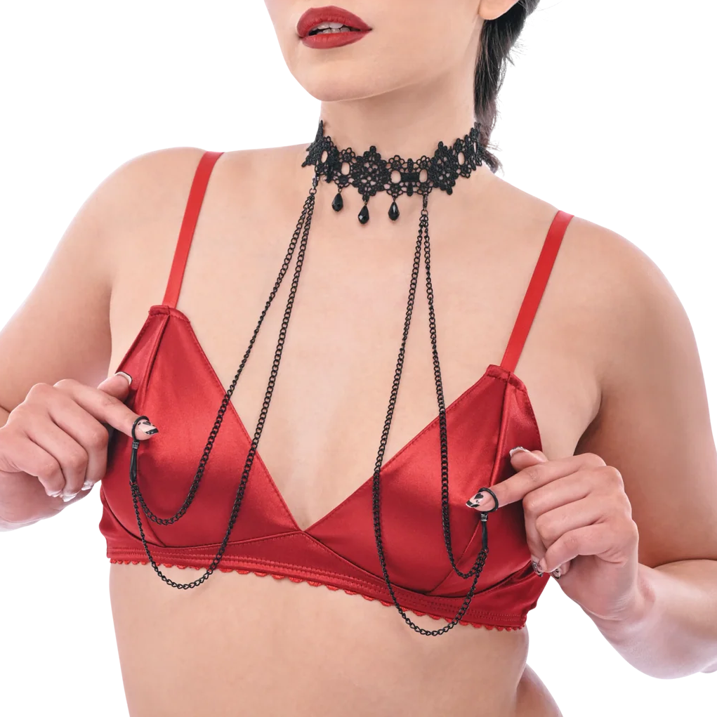 A woman modeling a red satin lingerie set with a matching red thong and red bra, accessorized with a black beaded choker and double chain drapes against a plain white background.