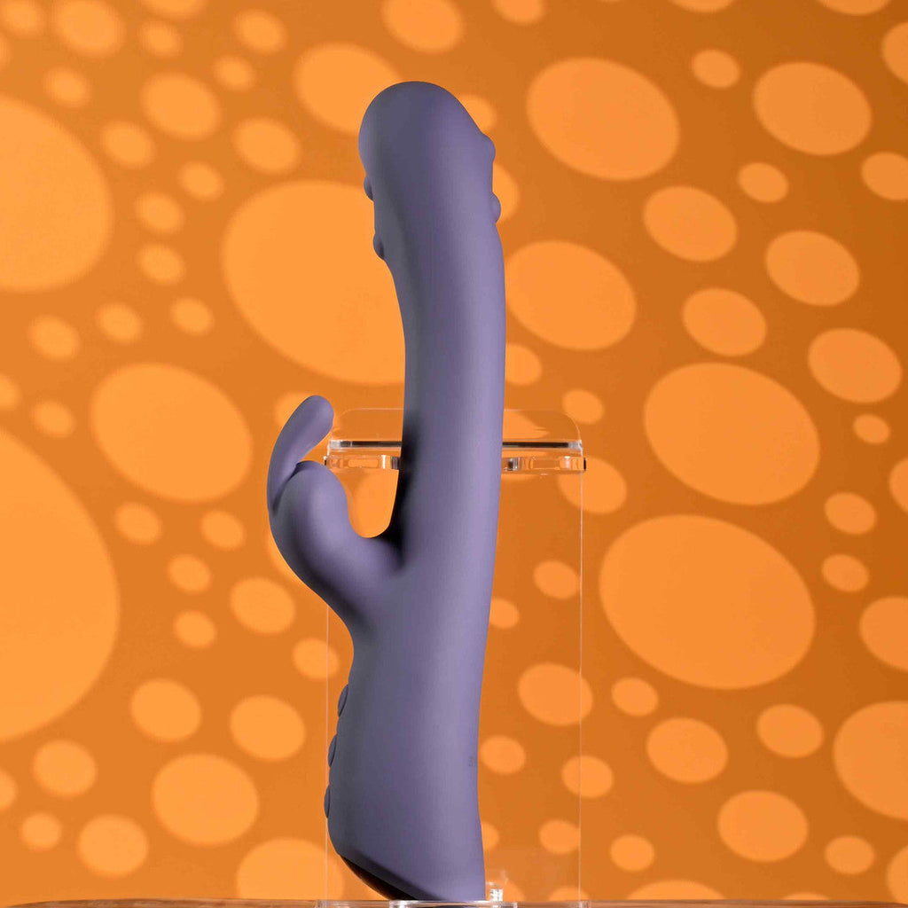 Purple toy with clear stand on a wooden surface against an orange polka dot background