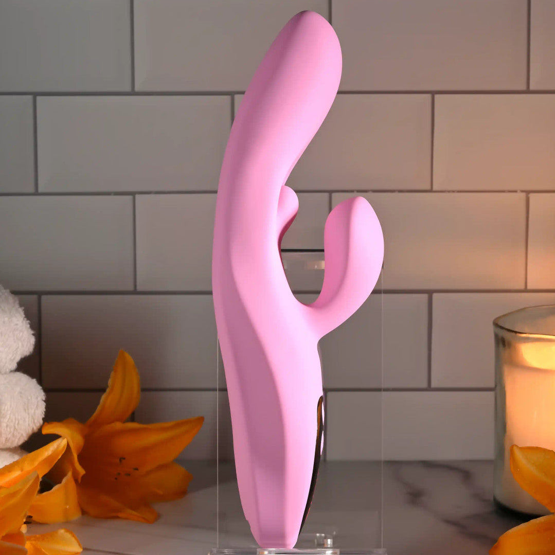 Pink electronic device on a stand with 'EvolvEd' branding, surrounded by flowers and a candle.