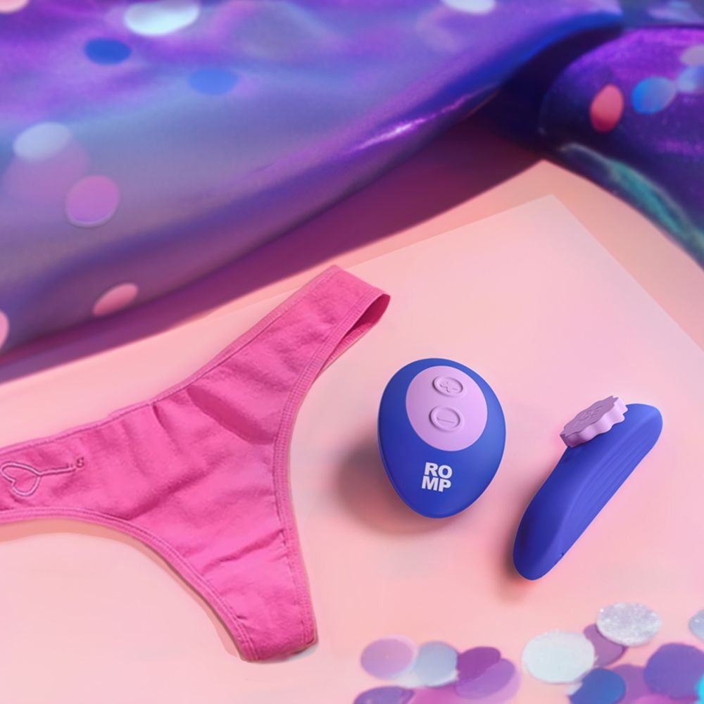 Pink women's underwear sitting next to a blue panty vibe on a colorful pool side background.