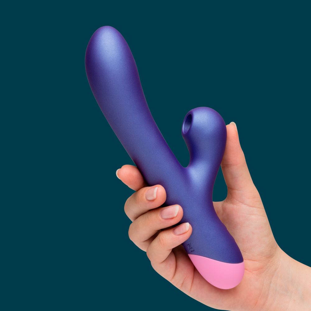 Purple and pink toy held in a hand against a dark blue background