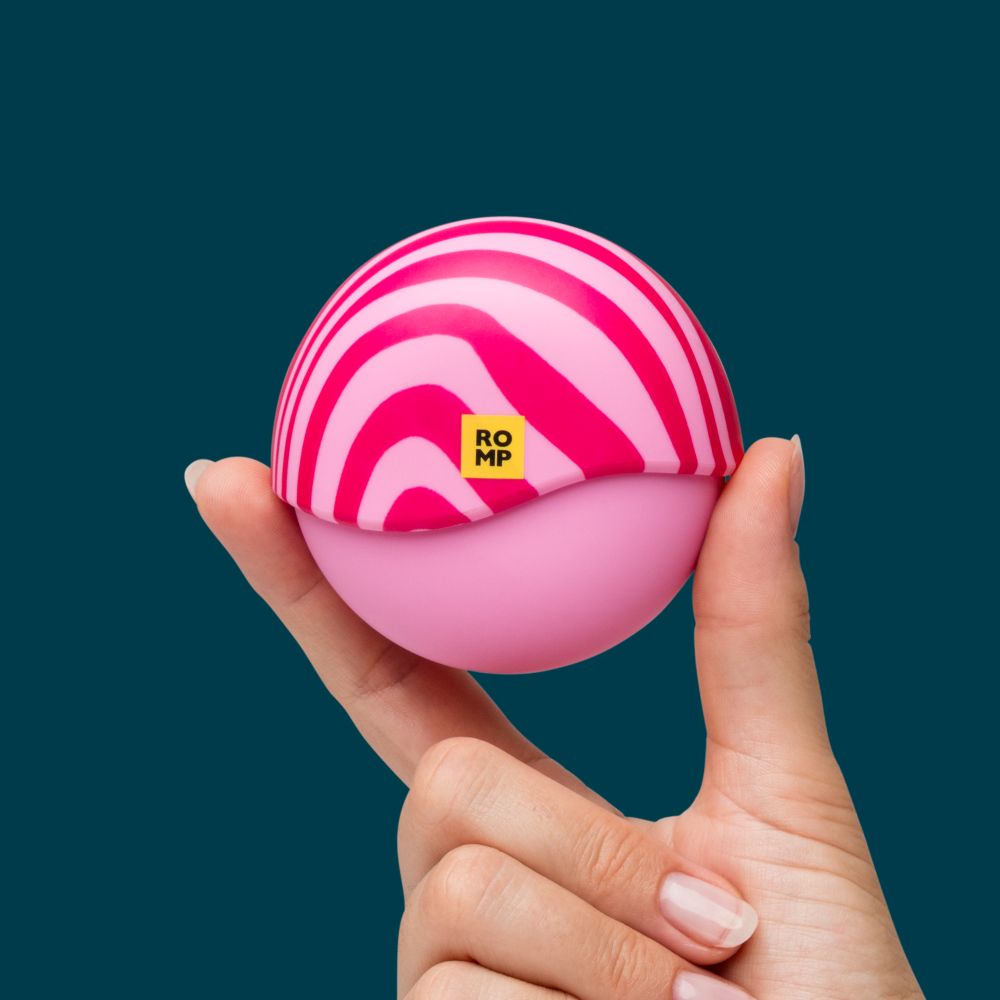Pink and white striped pleasure product that when the lid is closed, becomes a round circle. 