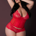 Woman wearing a red lace lingerie set against a dark background